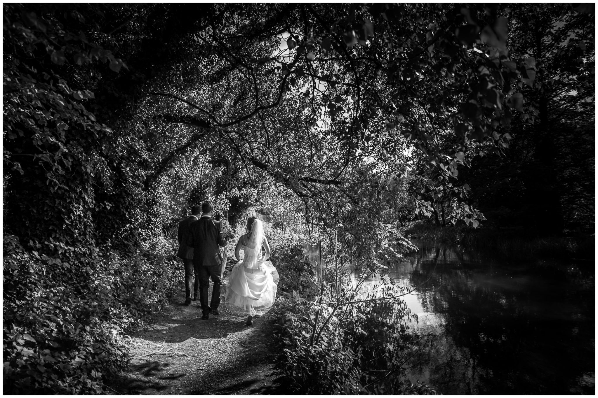 Black and white photo of wedding couple walking beside river