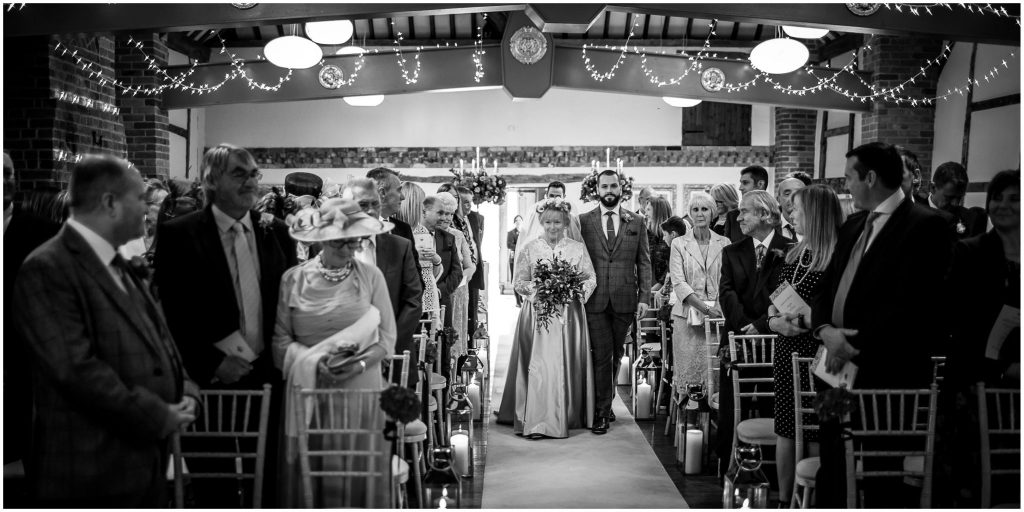 Black and white photo of bride walking down the aisle