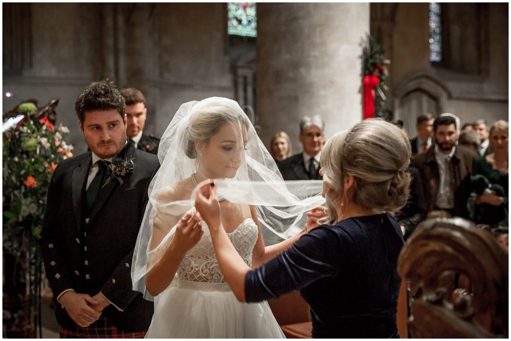 Bridesmaid lifts the bride's veil