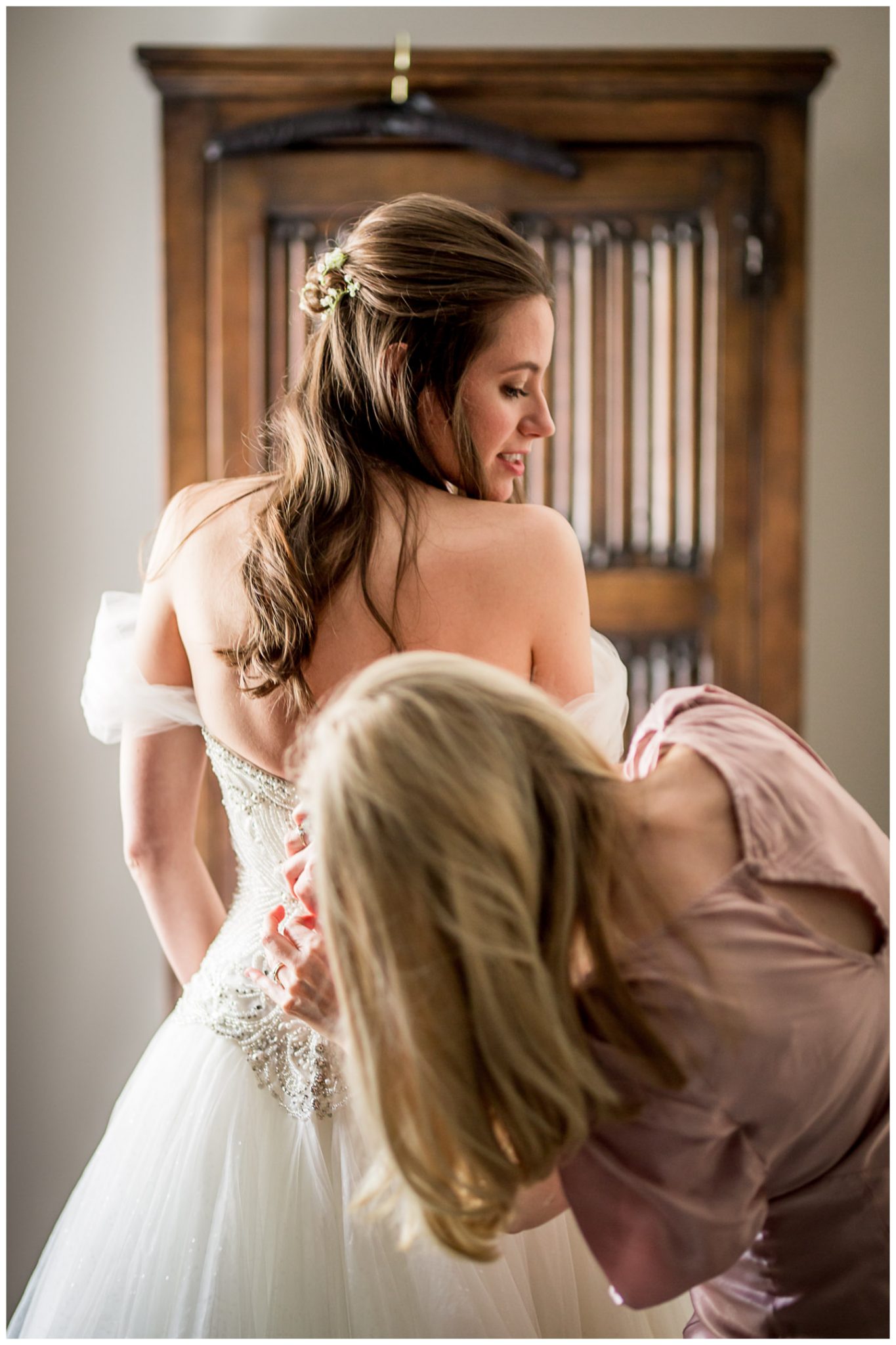 The bride is buttoned into her wedding dress