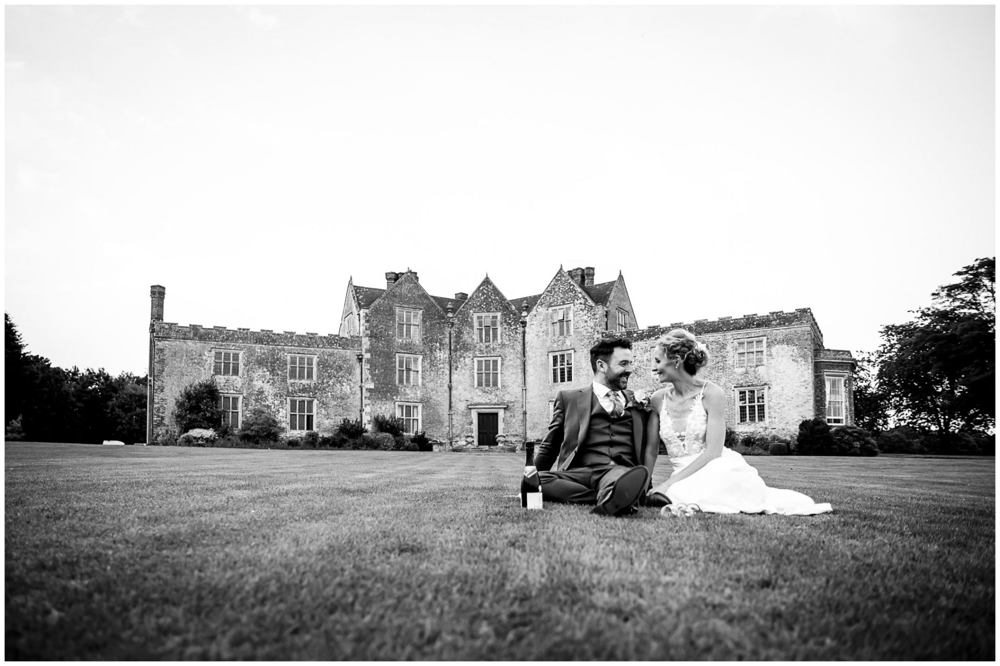 Black and white image of couple sat on the lawn in front of Newhouse Estate near Redlynch in the New Forest