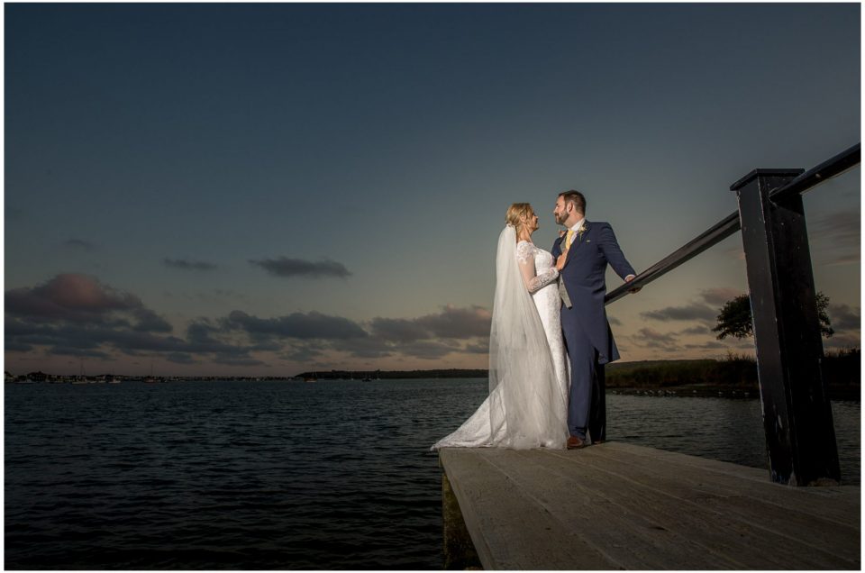 Couple stood on the jetty by the water in the evning light