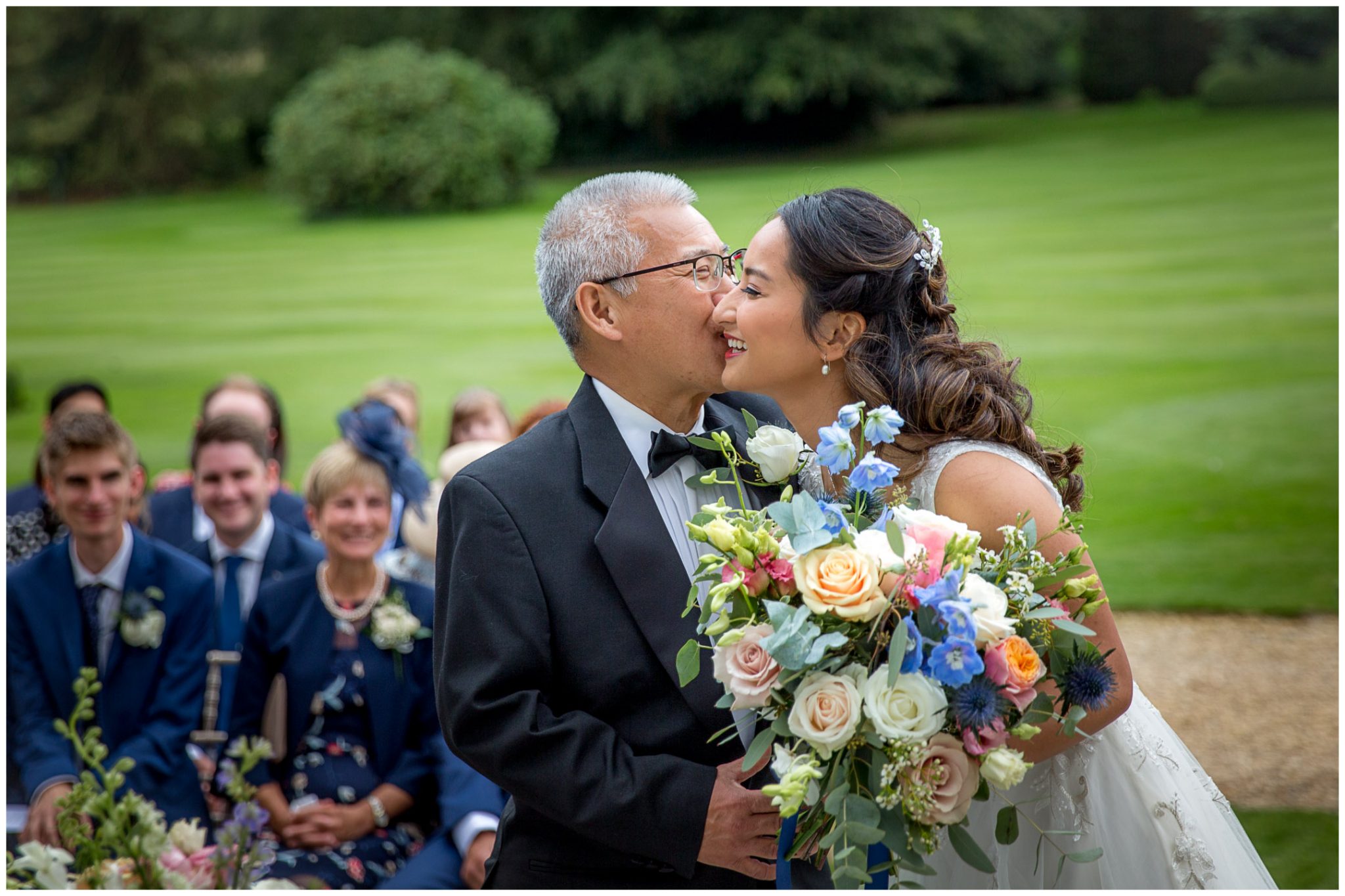 Father of the bride gives his daughter a kiss as they arrive at the front of the aisle