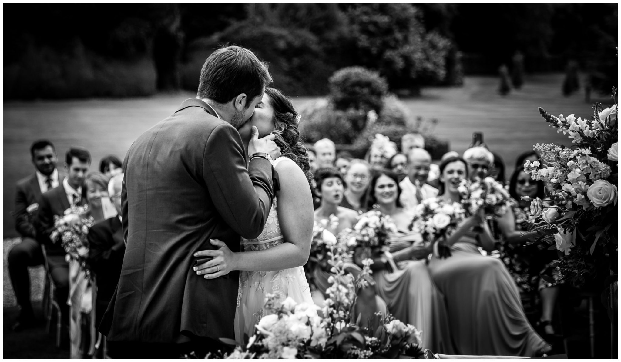 The groom kisses the bride during the ceremony, black and white documentary wedding photo