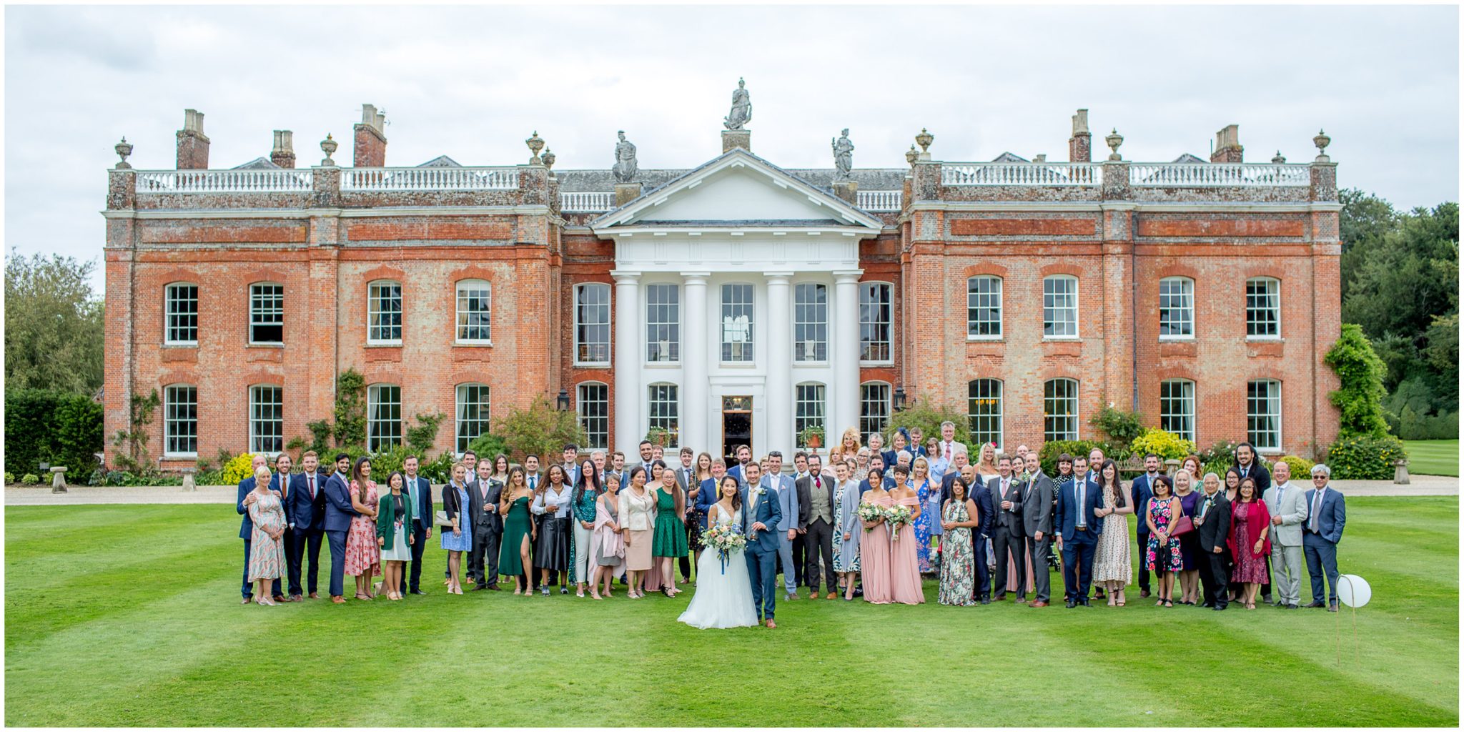Large group photos of wedding guests in front of the wedding venue