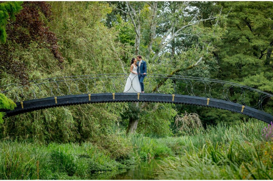 Couple stood on bridge for Summer wedding portrait at Avington Park Hampshire wedding venue