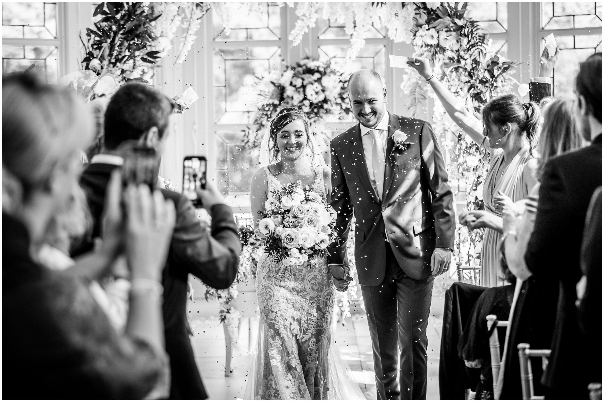 Guests throw confetti as the bride and groom walk back down the aisle