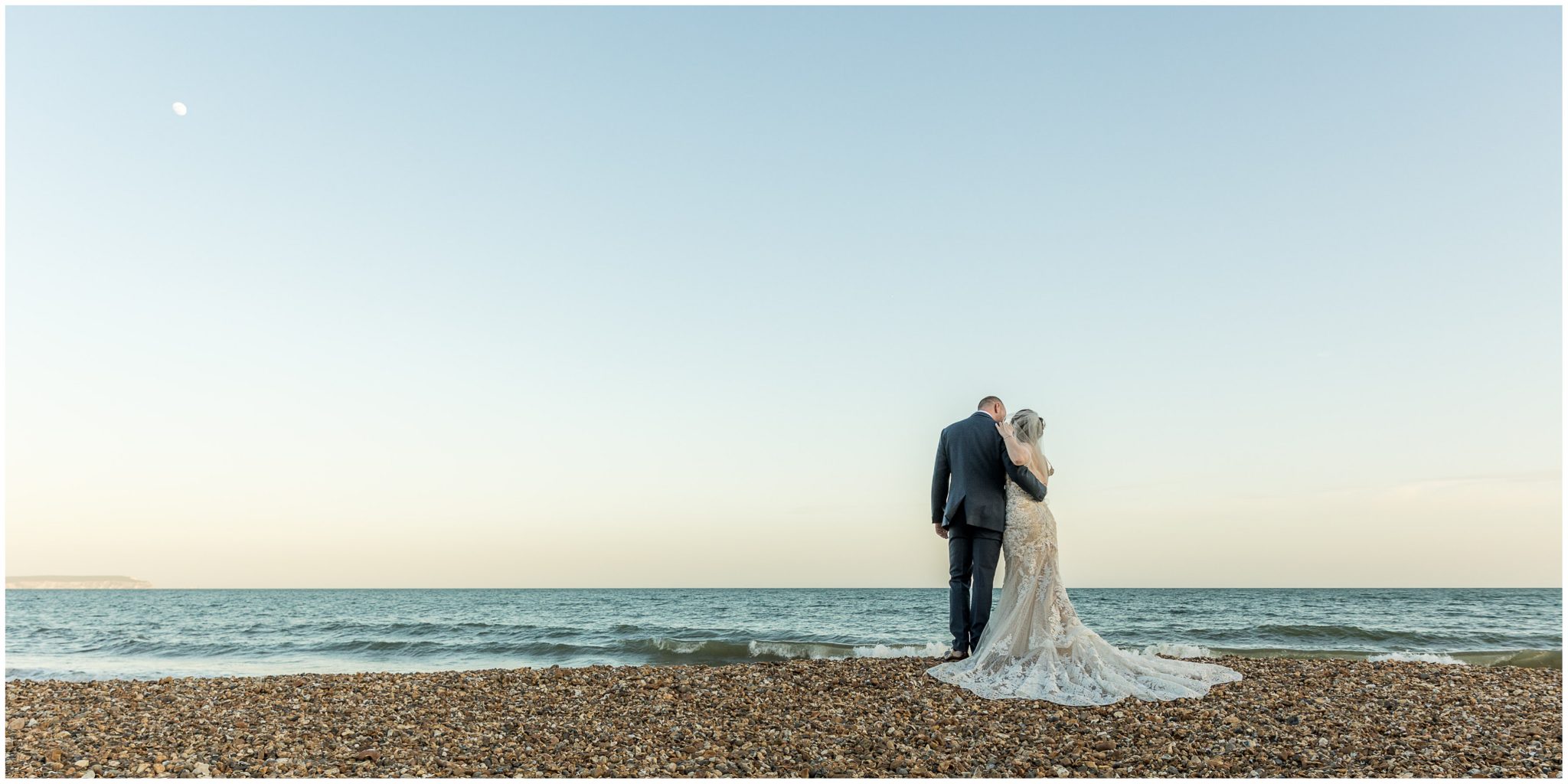 The couple look out over the blue seas on the Solent during their seaside beach photo shoot