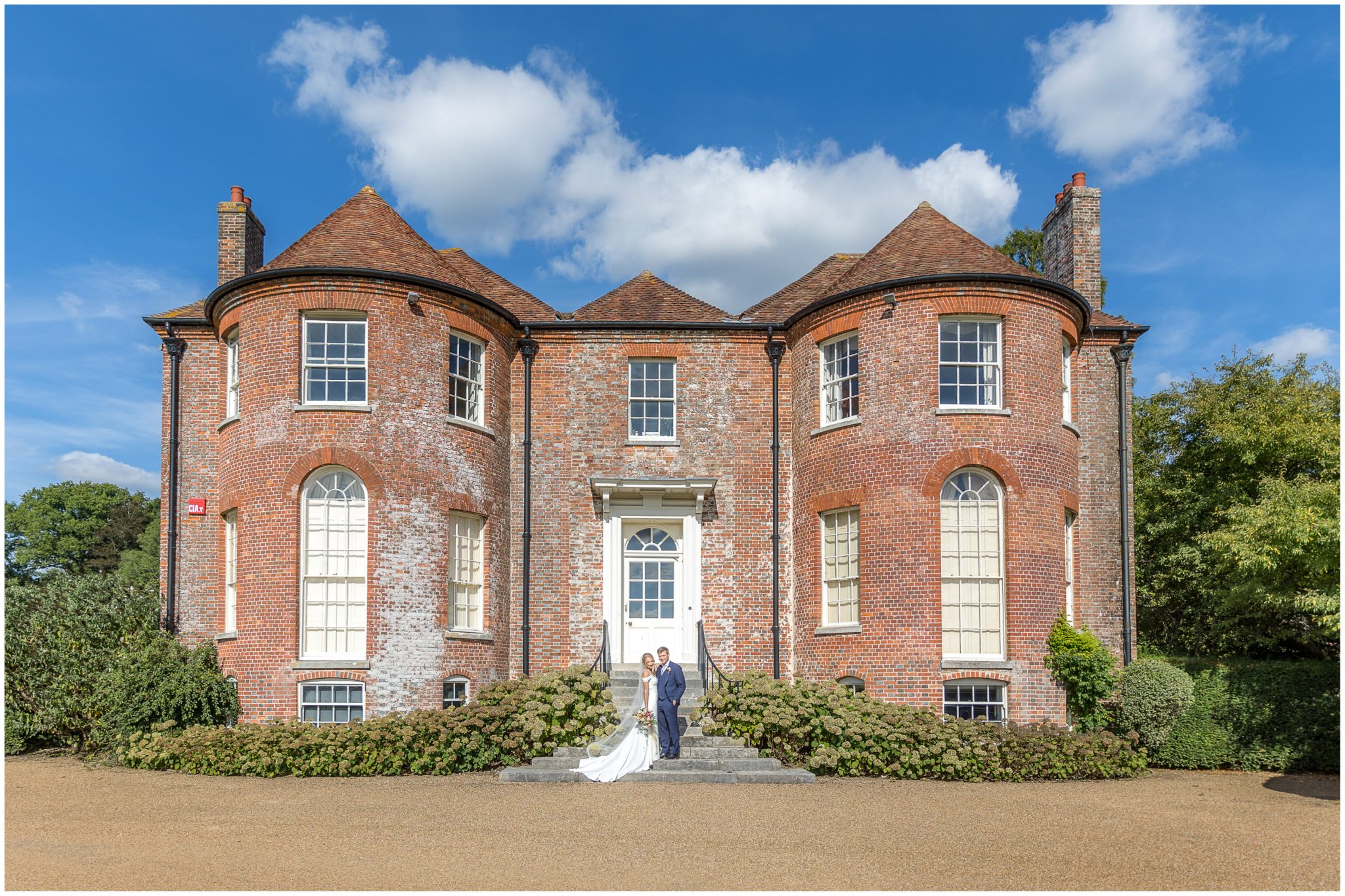 Bride and groom stood in front of main house at he Holywell Estate in Hampshire