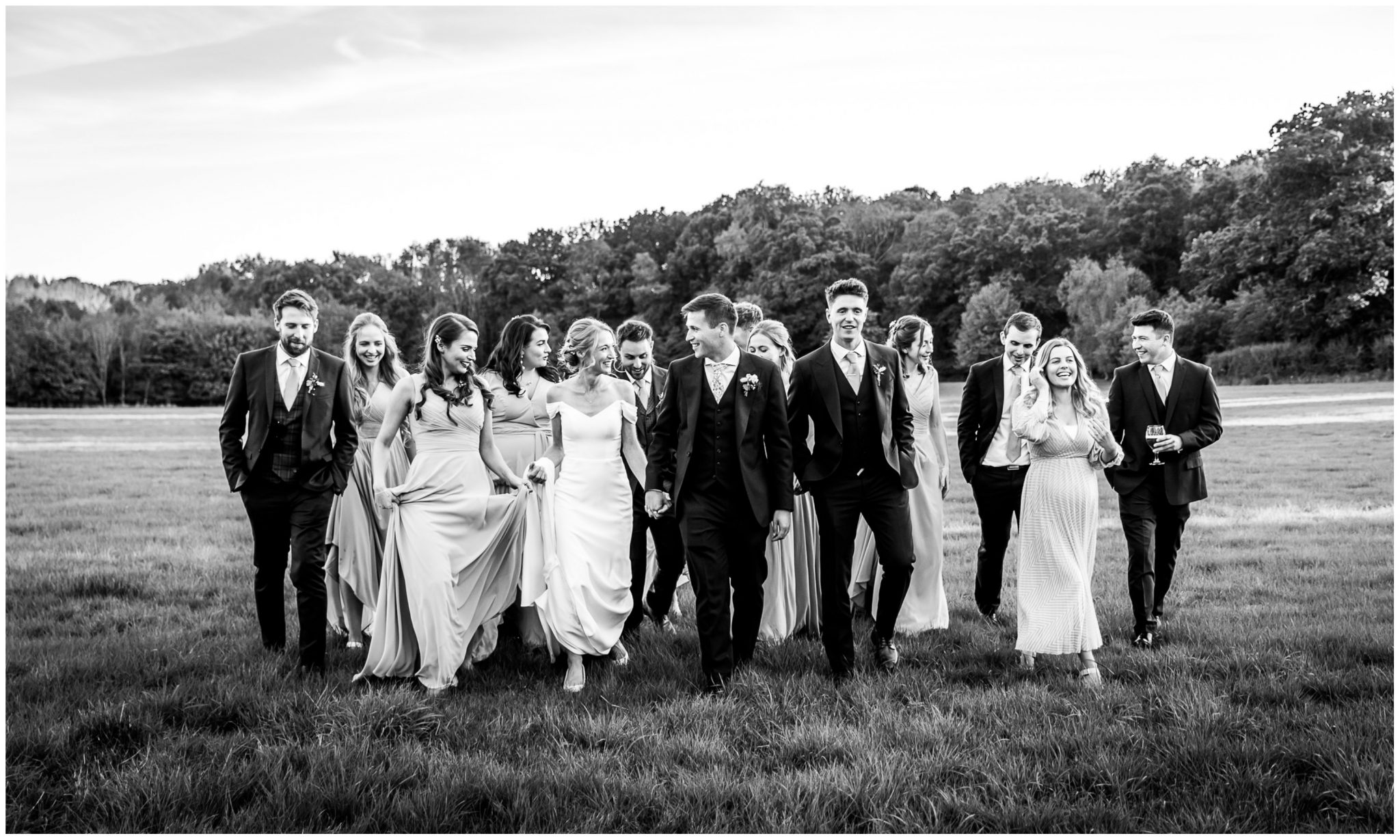 B;ack and whote candid photo of couple with wedding party in the grounds of the Holywell Estate