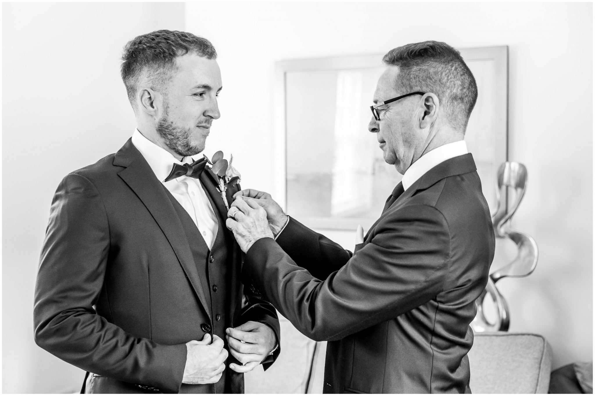 Father of the groom pins a buttonhole flower on his son's suit