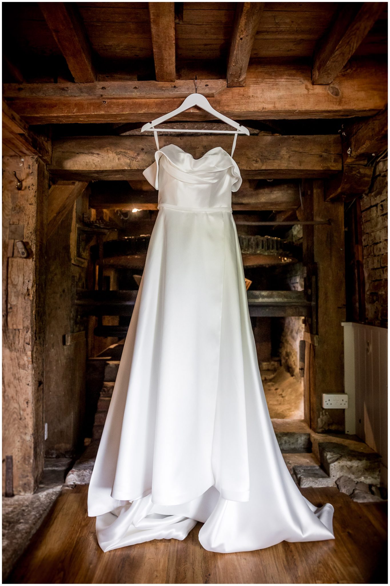 Wedding dress hanging in front of the old workings of the water mill