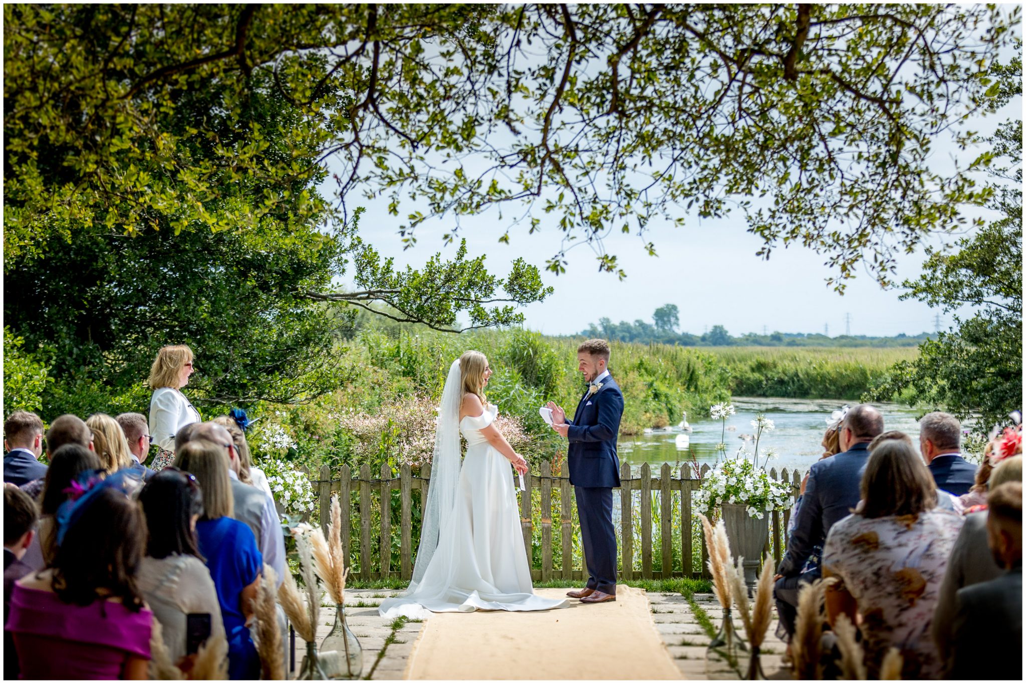 Bride and groom facing each other at the outdoor riverside ceremony setting in Dorset