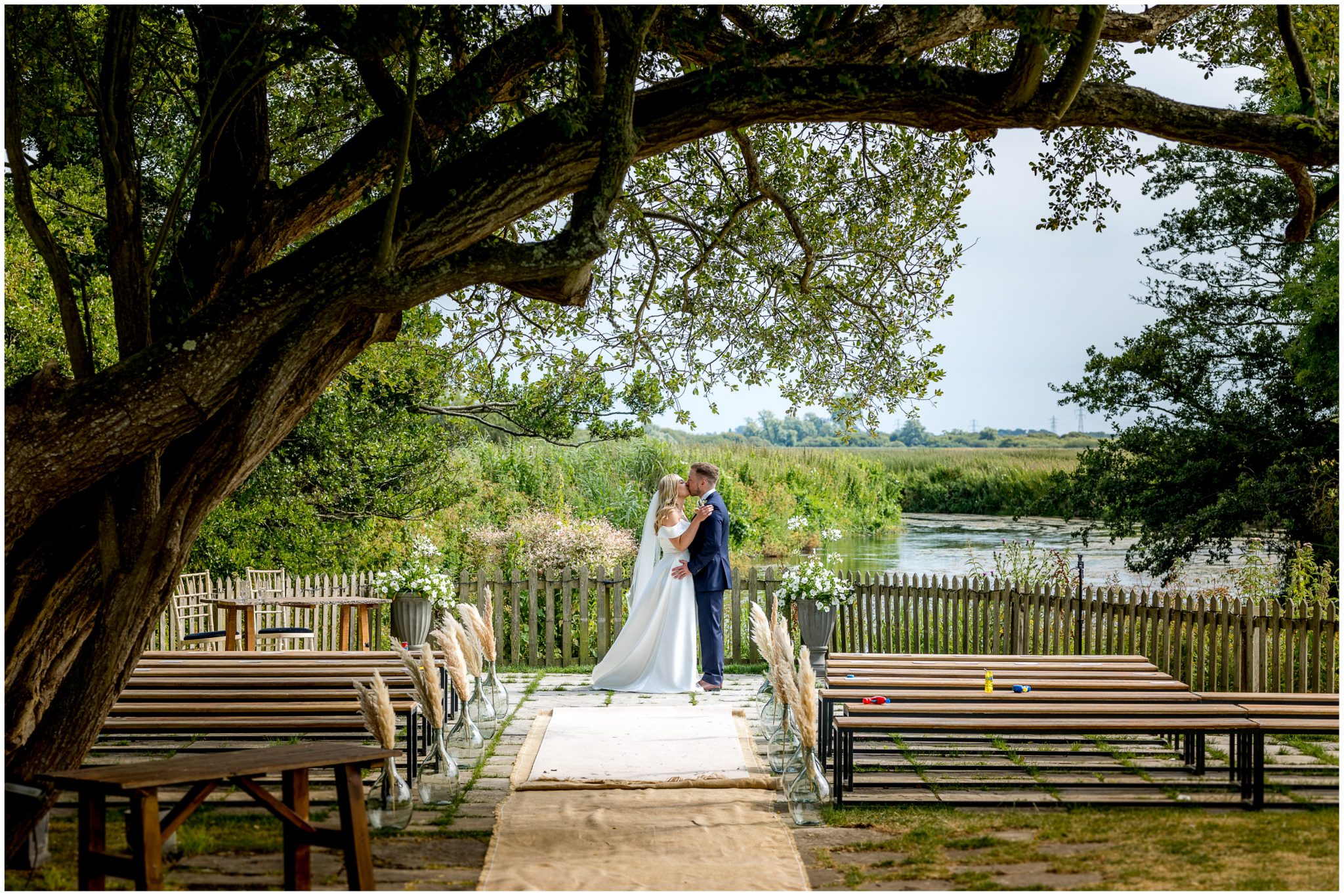 The bride and groom kiss with the river as a backdrop during their couple portraits session