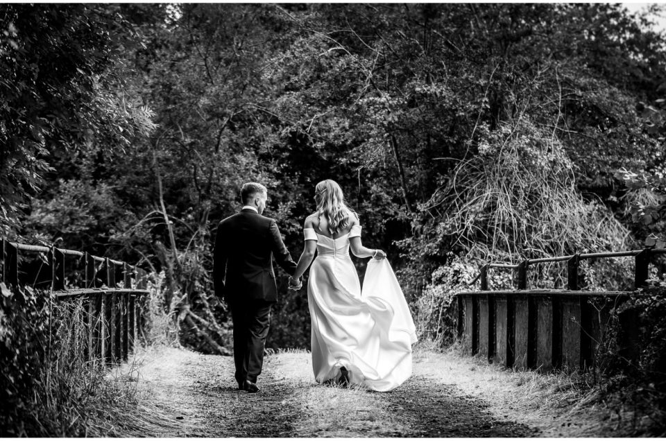 Black and white couple portrait walking away from camera over the bridge