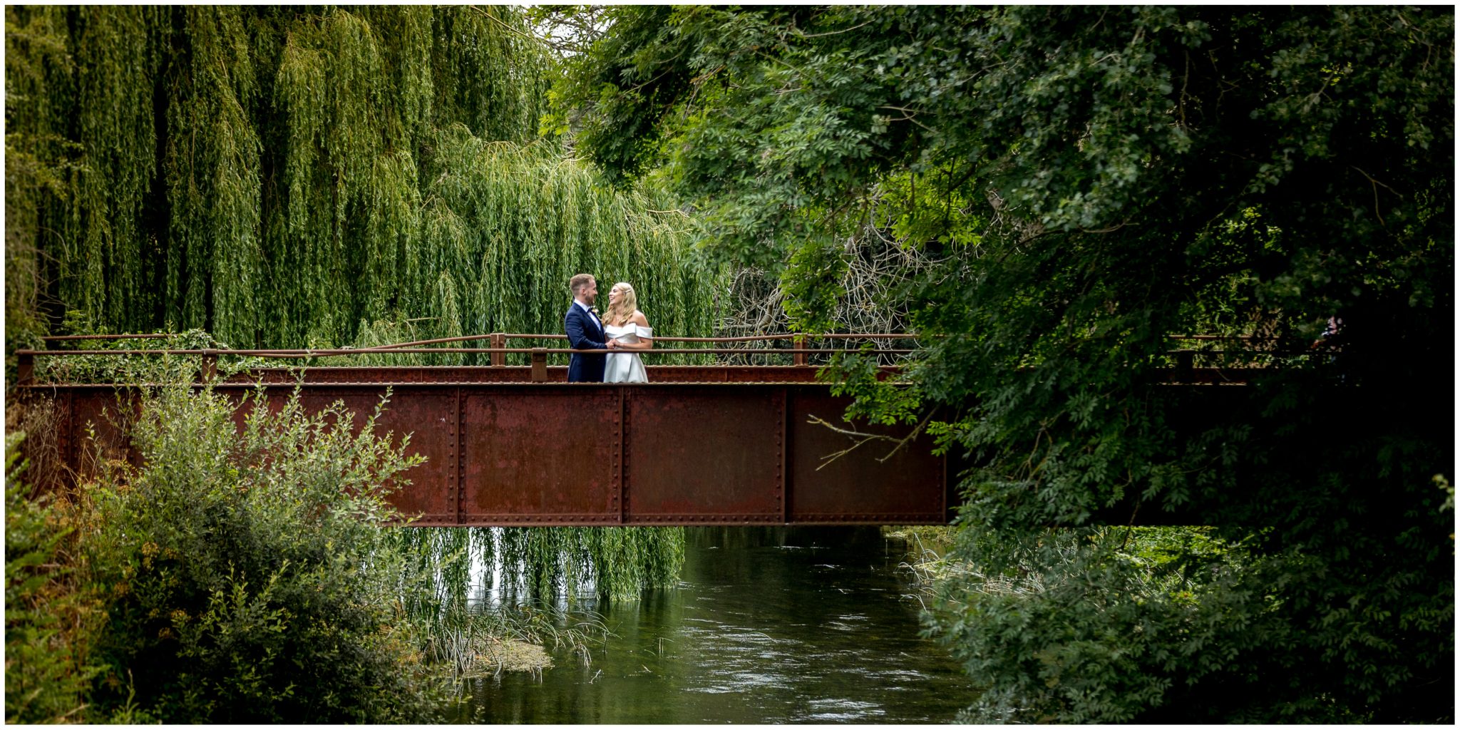 Bride and groom stood on the iron bridge behind Sopley Mill