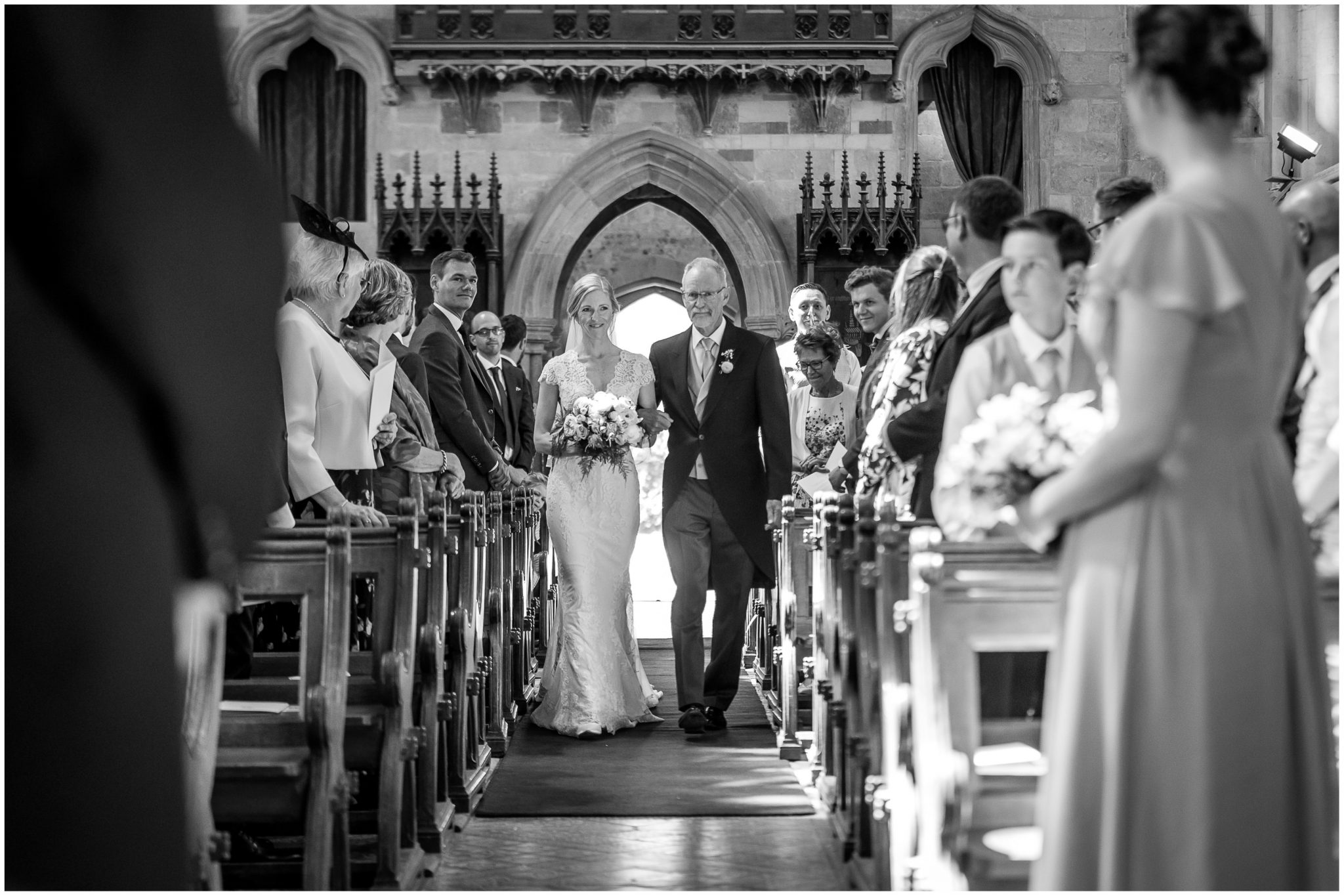 The bride walking down the aisle on her father's arm in a Dorset countryside church