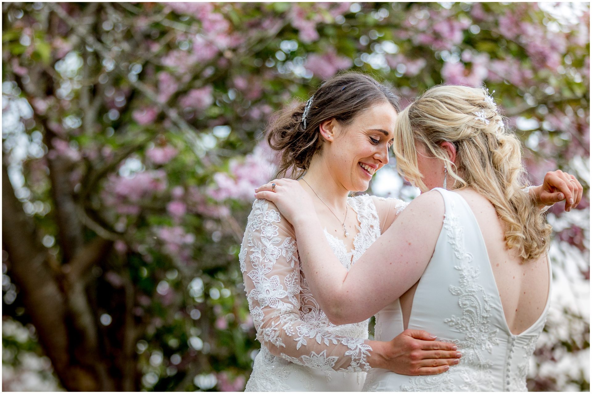 Same sex bride portrait in front of blossom tree at Hampshire wedding venue in the Spring