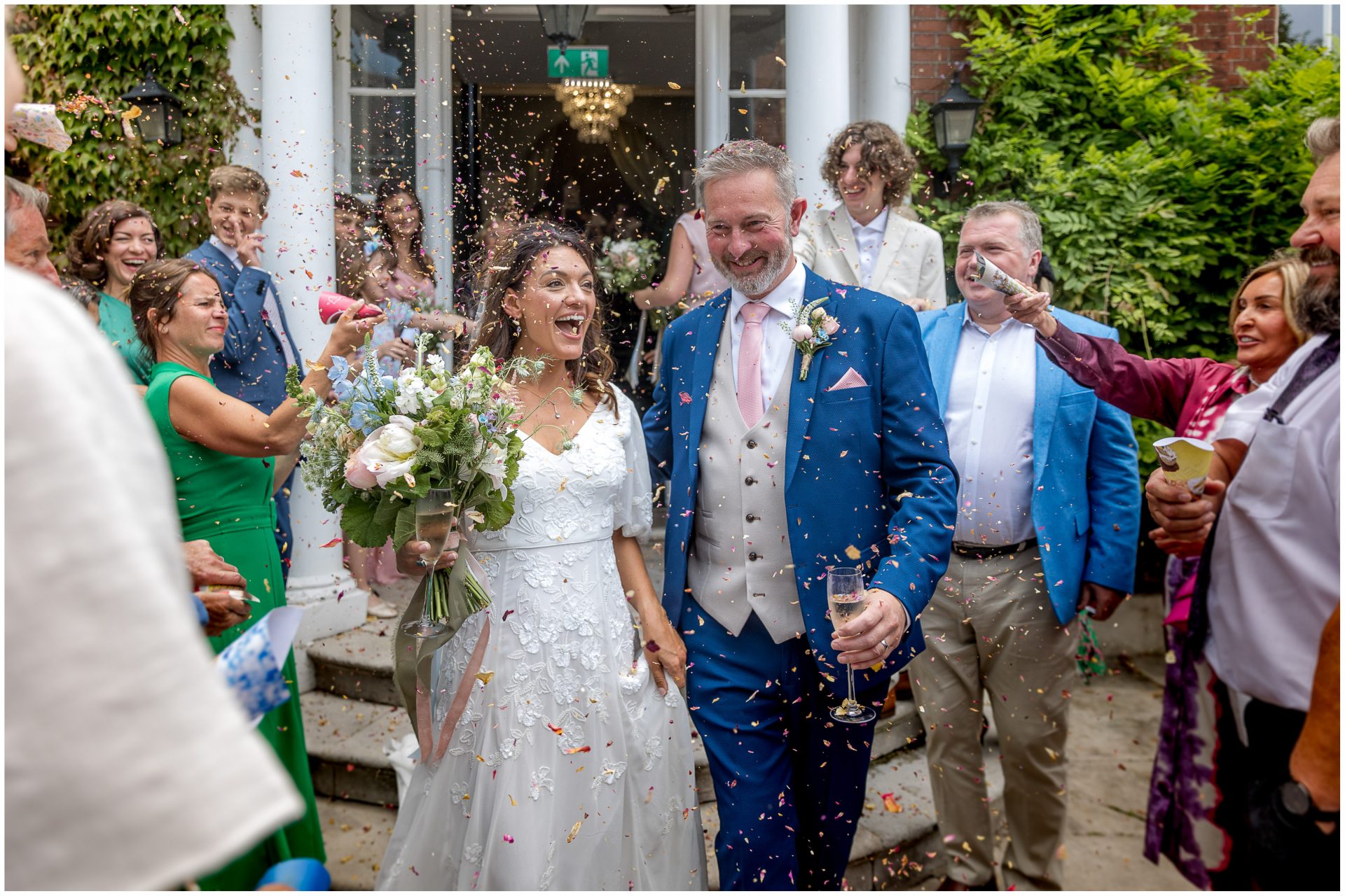 Guests shower the couple in confetti as they exit the Hotel du Vin Poole wedding venue by the impressive front entrance