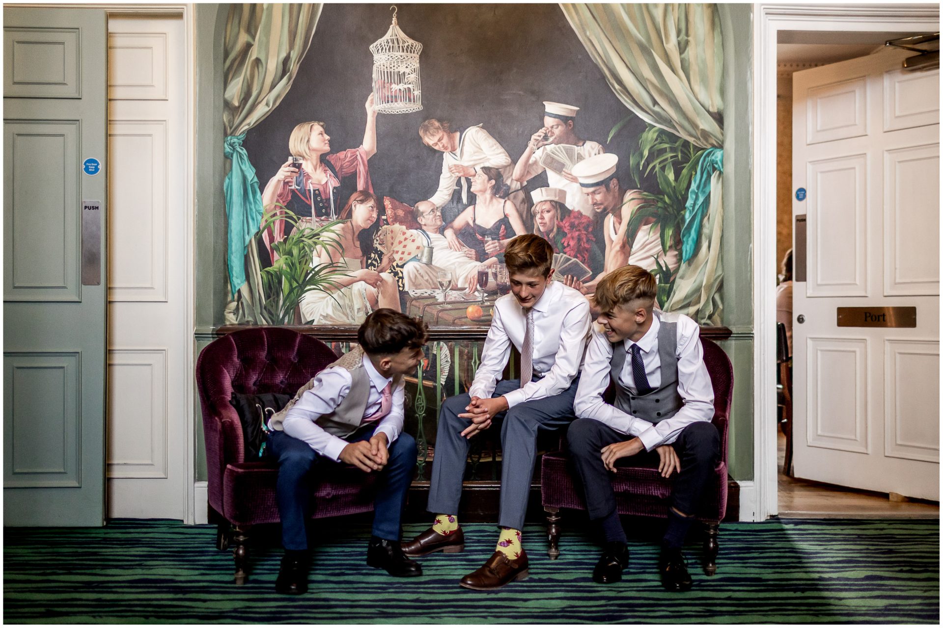 Three young men sitting in front of the mural on the hotel staircase